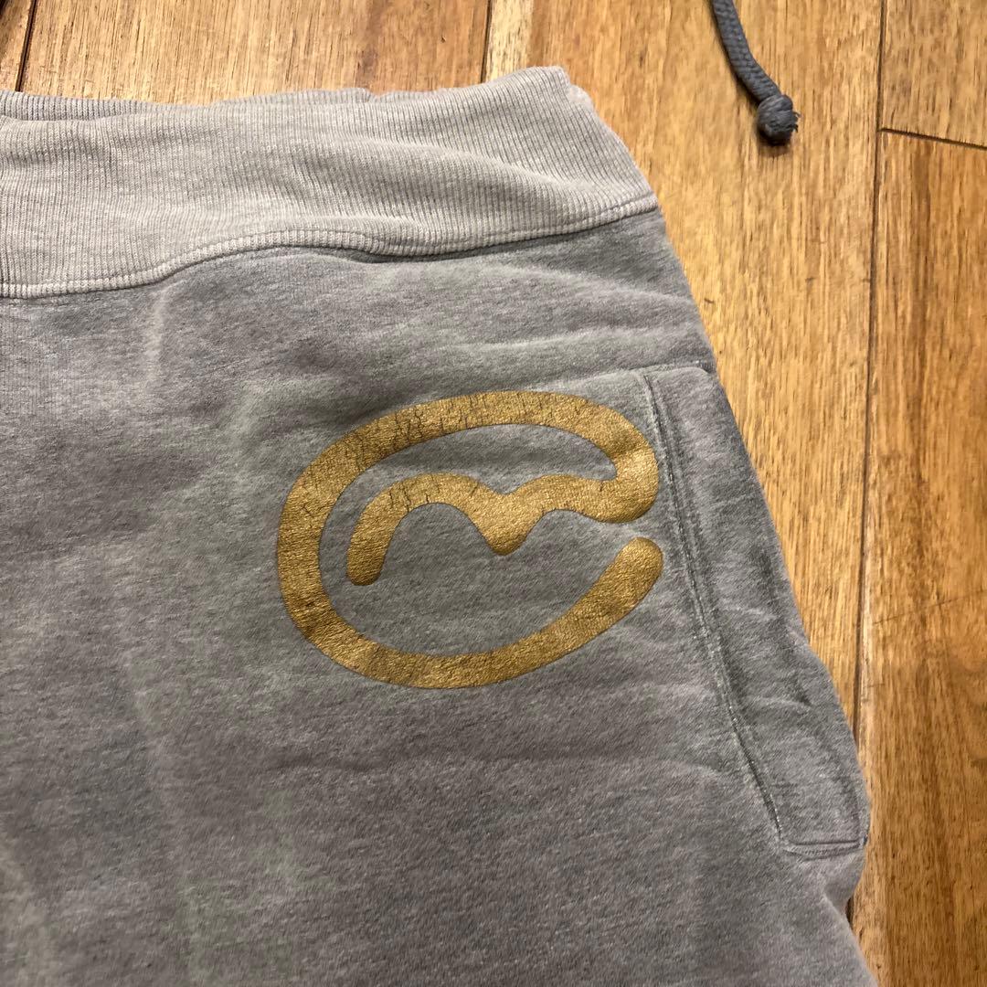 グレー スウェットパンツ 赤いパッチ 金色ロゴ