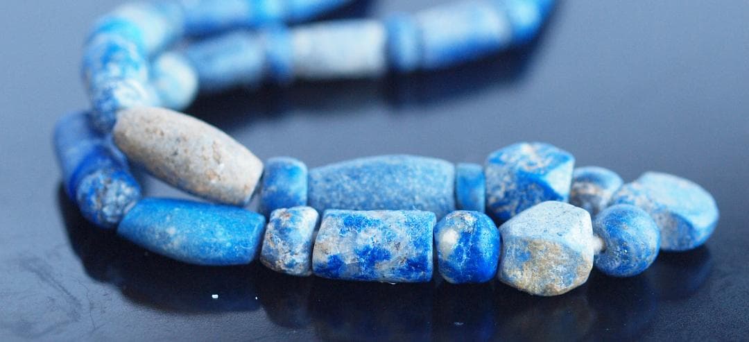 古代濃紺ラピスの管玉や丸玉をほぼ左右対称に編み、トップに斧型や多面体、80個の連