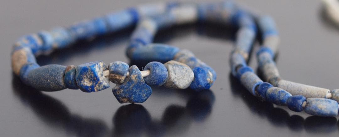 古代濃紺ラピスの管玉や丸玉をほぼ左右対称に編み、トップに斧型や多面体、80個の連